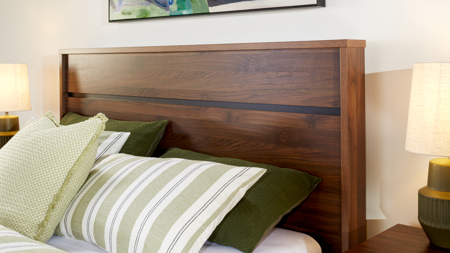 Finn Walnut finish bed frame headboard with pillows styled against it and a bedside table and lamp to the side of it.