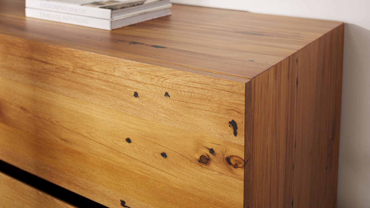 Close-up of the rustic wood grain, knots, and solid top on the corner of the six-drawer dresser