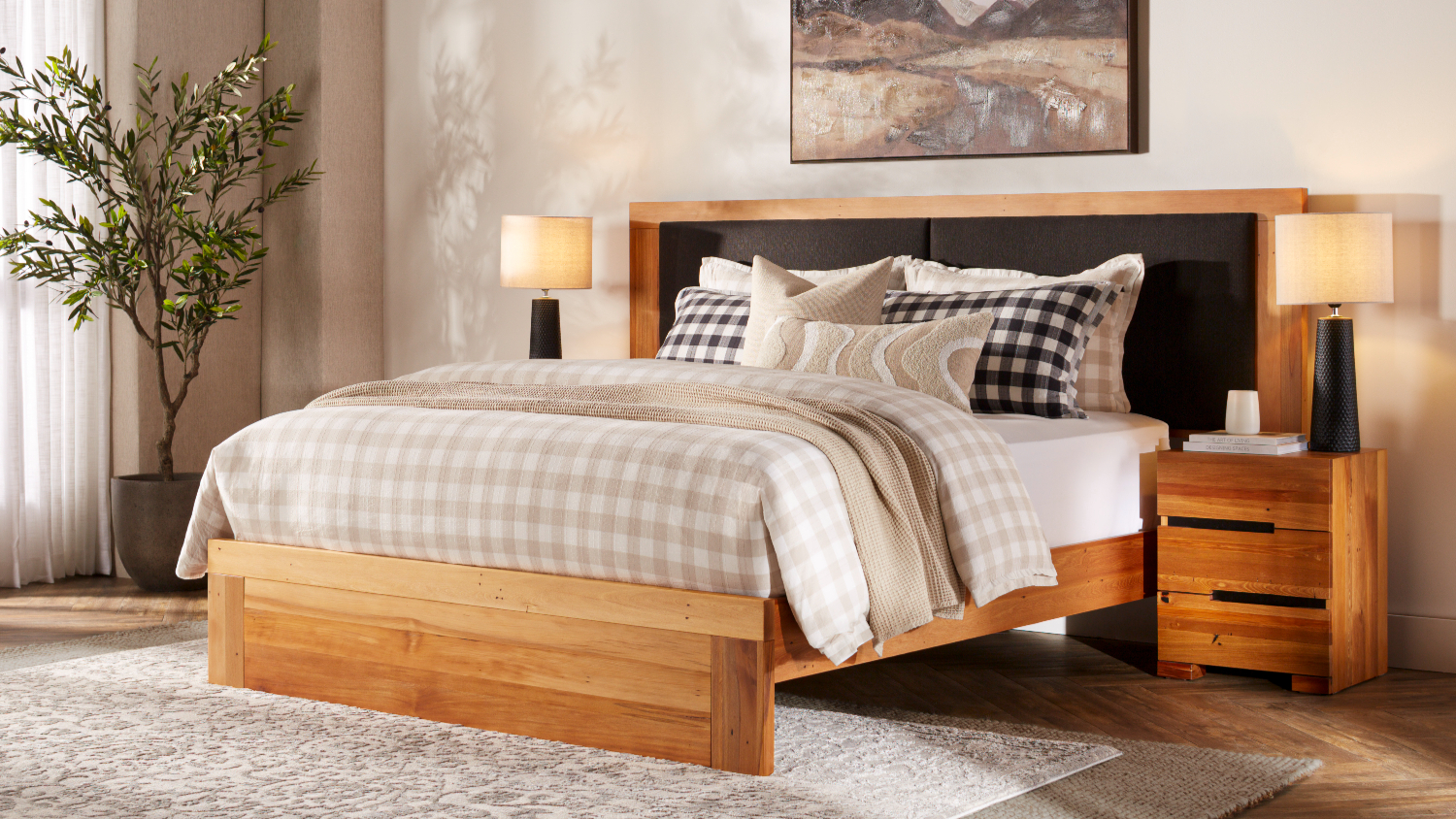 Wooden Nelson’s super king bed frame with a black upholstered headboard and checkered duvet and pillows