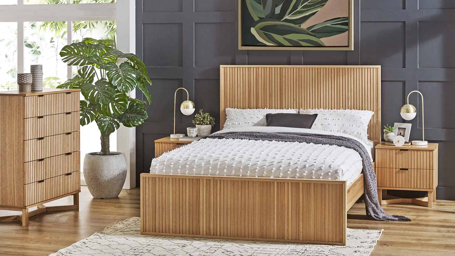 Full view of wooden slatted bed, chest of drawers, nightstands, and wall art