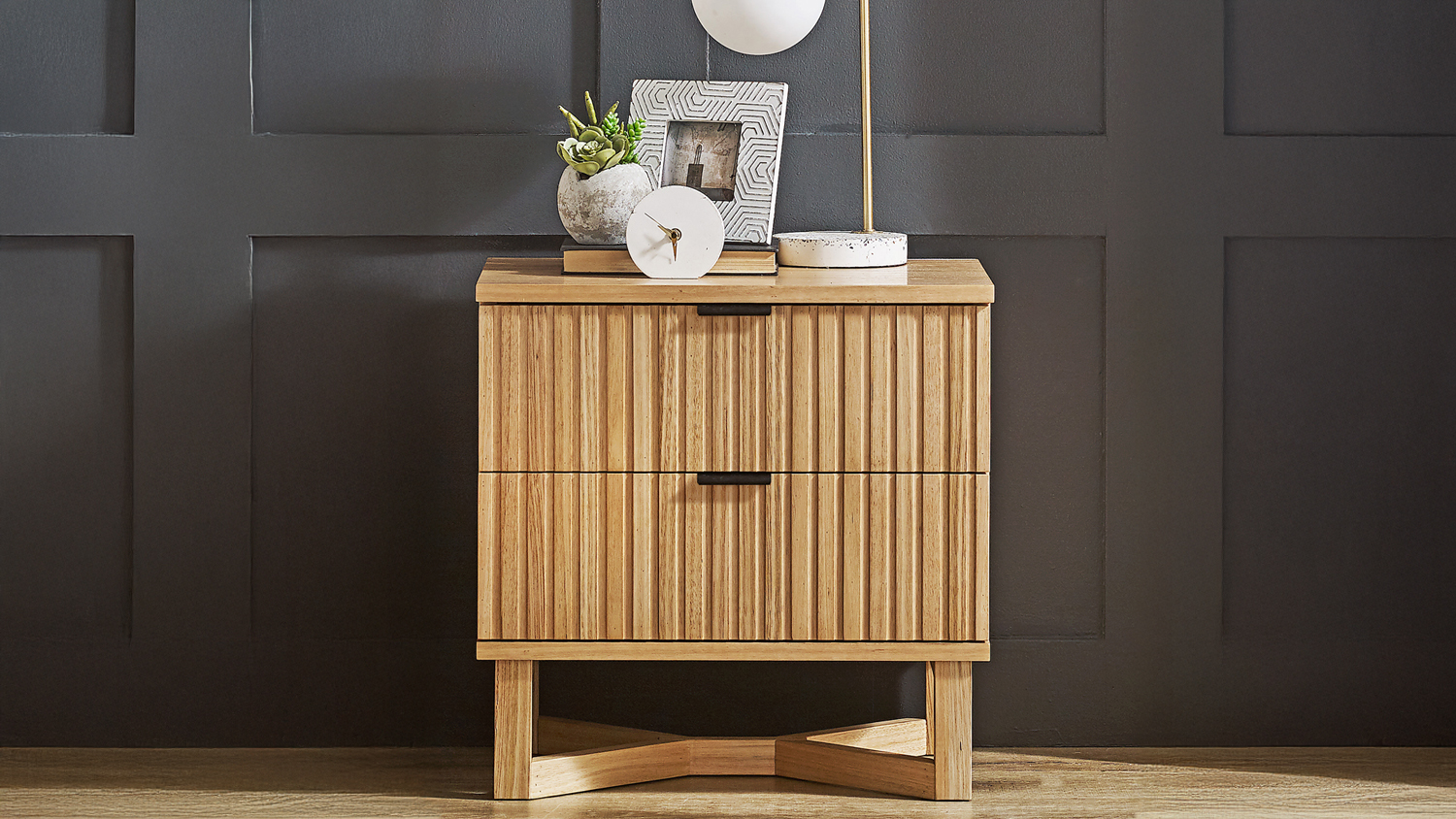 Close-up of a wooden nightstand with two slatted drawers and decorative items