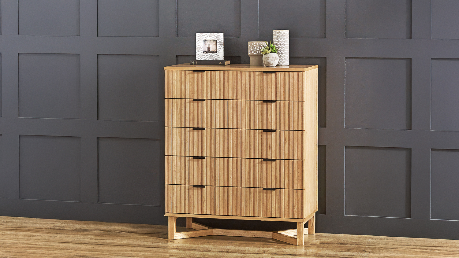 Natural wood chest of drawers with five slatted fronts and decorative accents