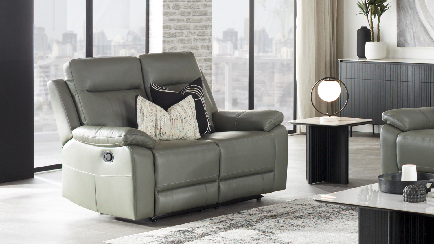 Front-facing view of a contemporary Nomad 2 Seater Leather Recliner Sofa in a bright, modern living room