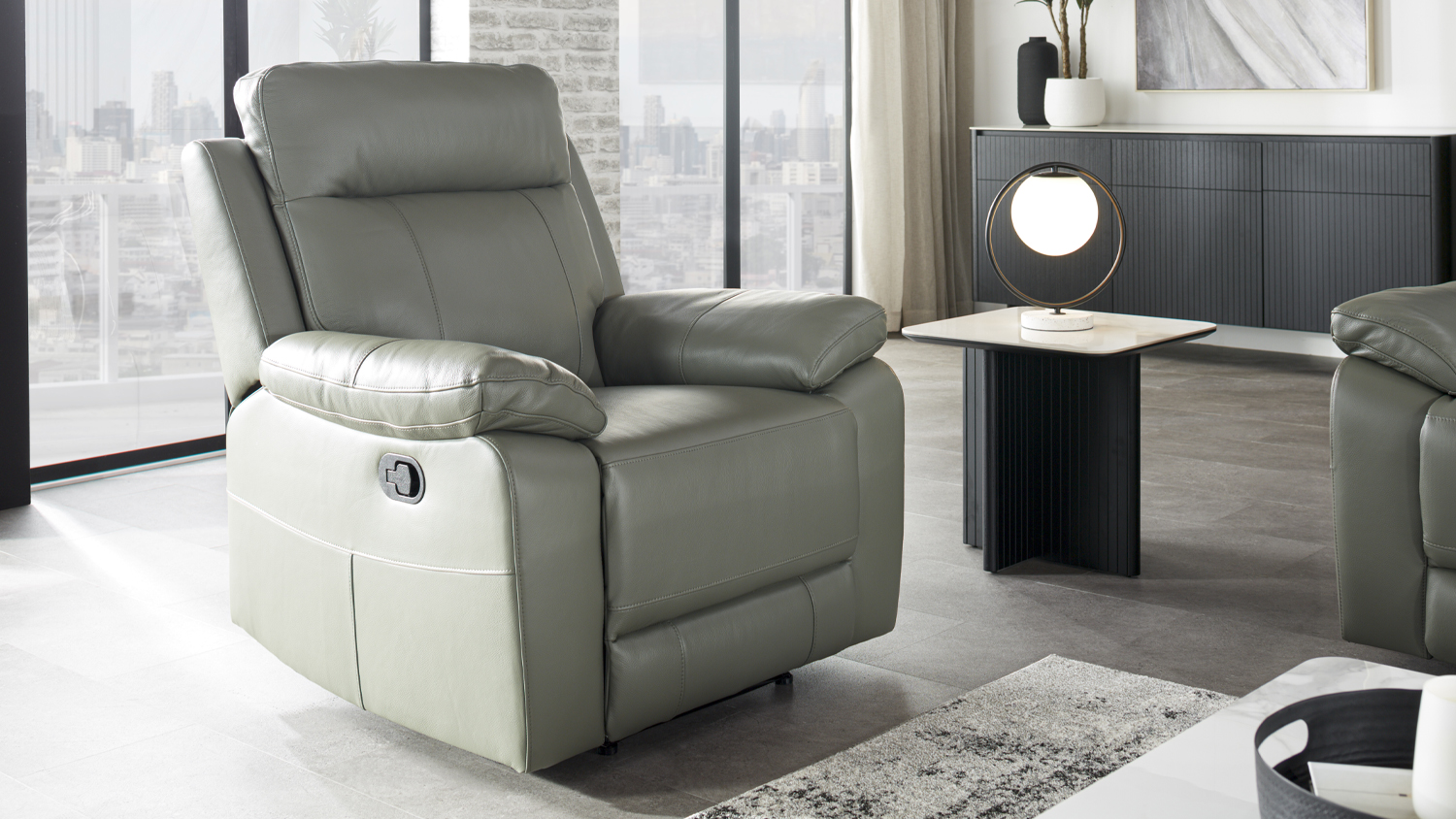 Nomad Leather Recliner Chair in platinum colour, featuring a high backrest and plush padded armrests in a modern room
