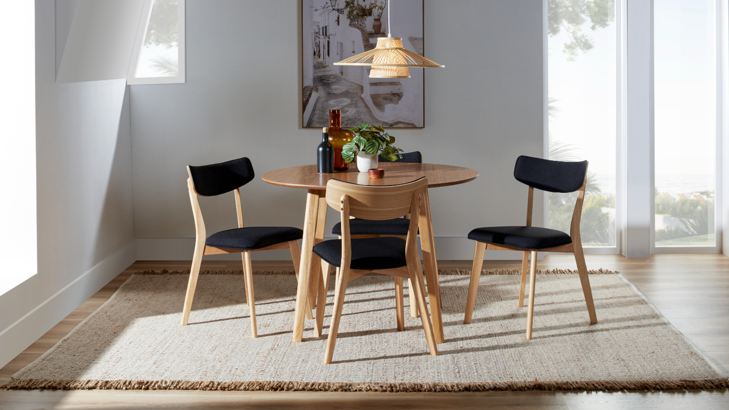 Zara drop leaf dining suite with a round wooden table and four chairs with black cushioned seats