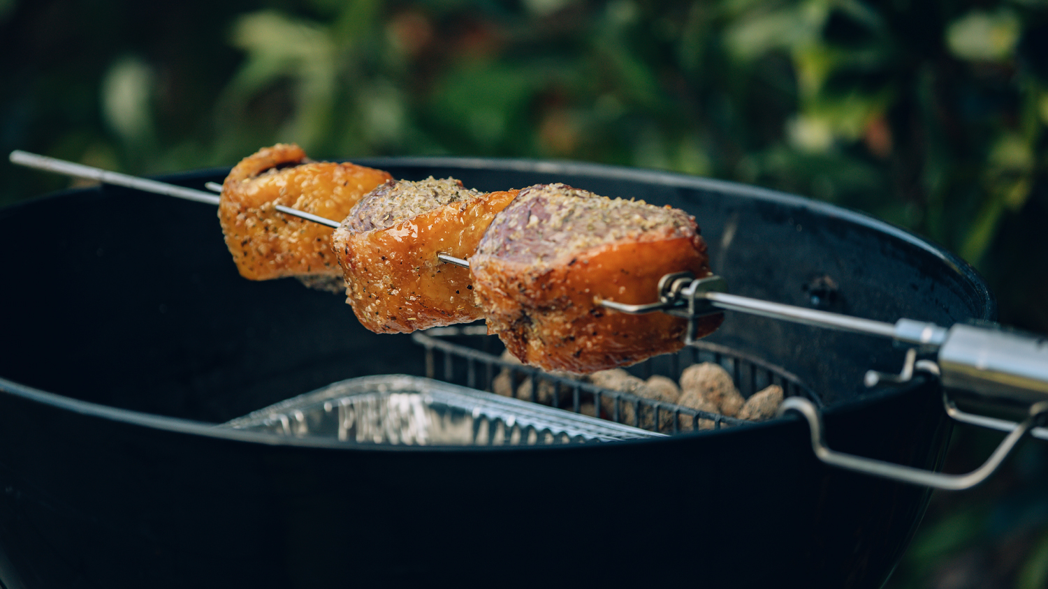 A view of cuts of meat being roasted over a BBQ
