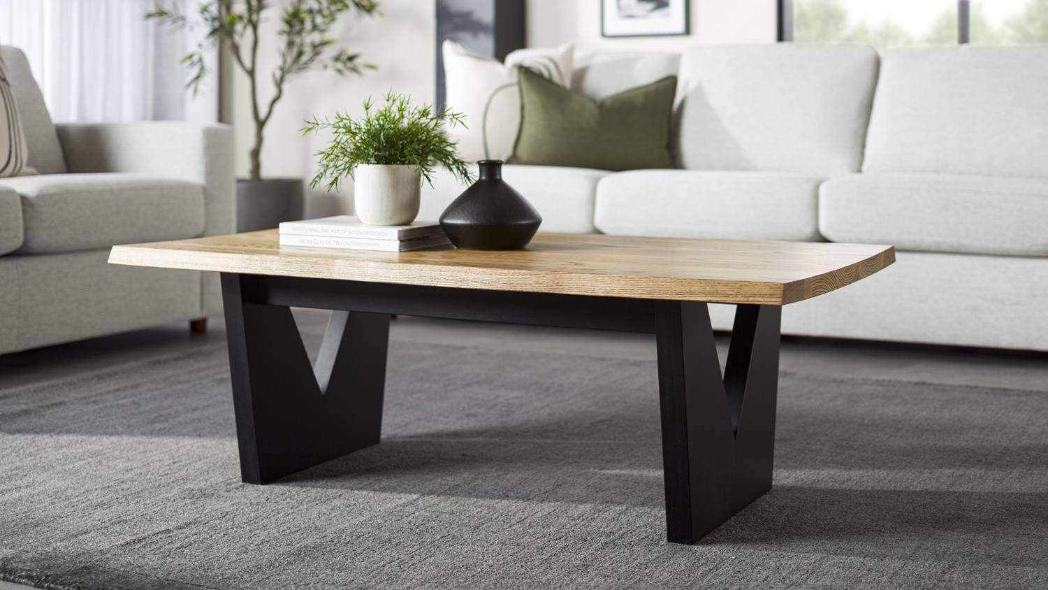 Raglan Coffee Table with a natural wood top and black V‑shaped legs, shown in a living room setting