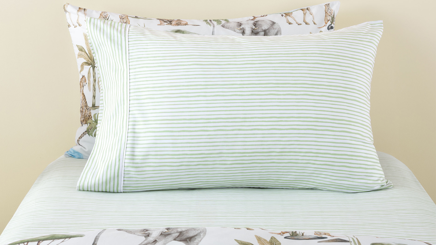 Scribble Stripe Green Sheet Set by Squiggles on a bed with safari accent pillow behind