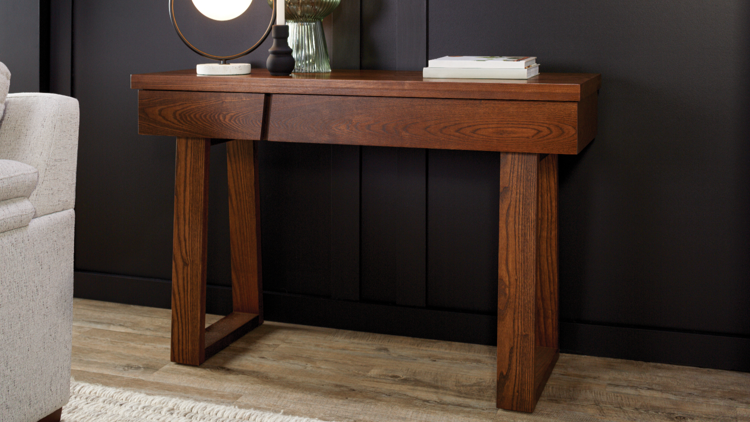Front view of a Haast 1200mm Hall Table in dark wood against a black wall