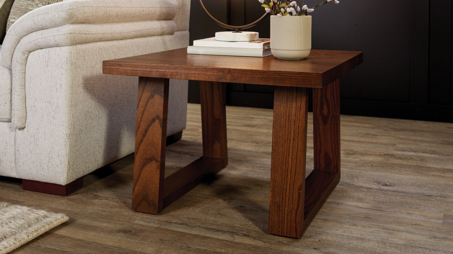 A modern Haast 650mm wood lamp table with a books and a vase on top in a living room