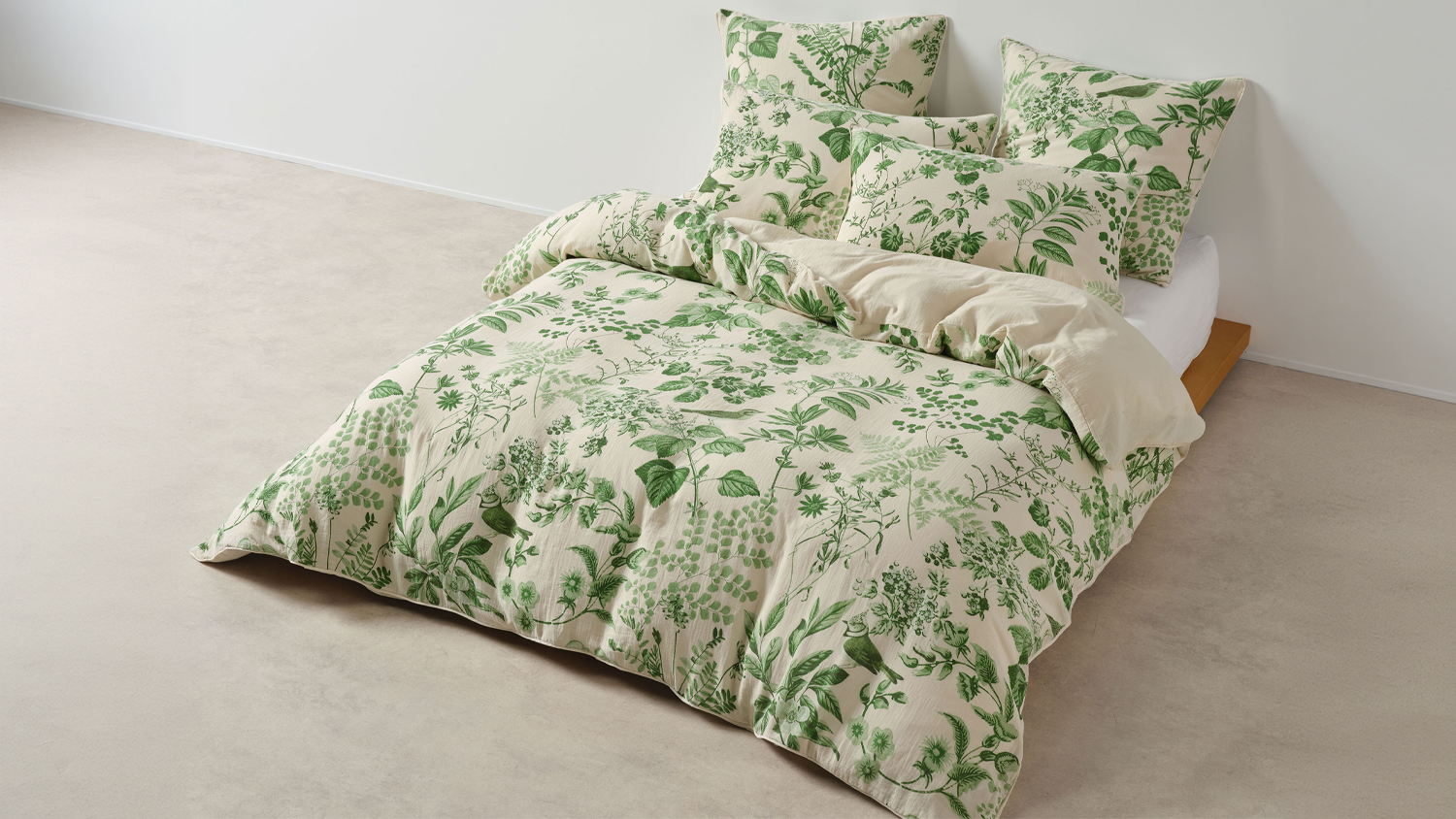 Bed made with the Lindy Natural duvet cover set featuring a cream base with detailed green botanical illustrations