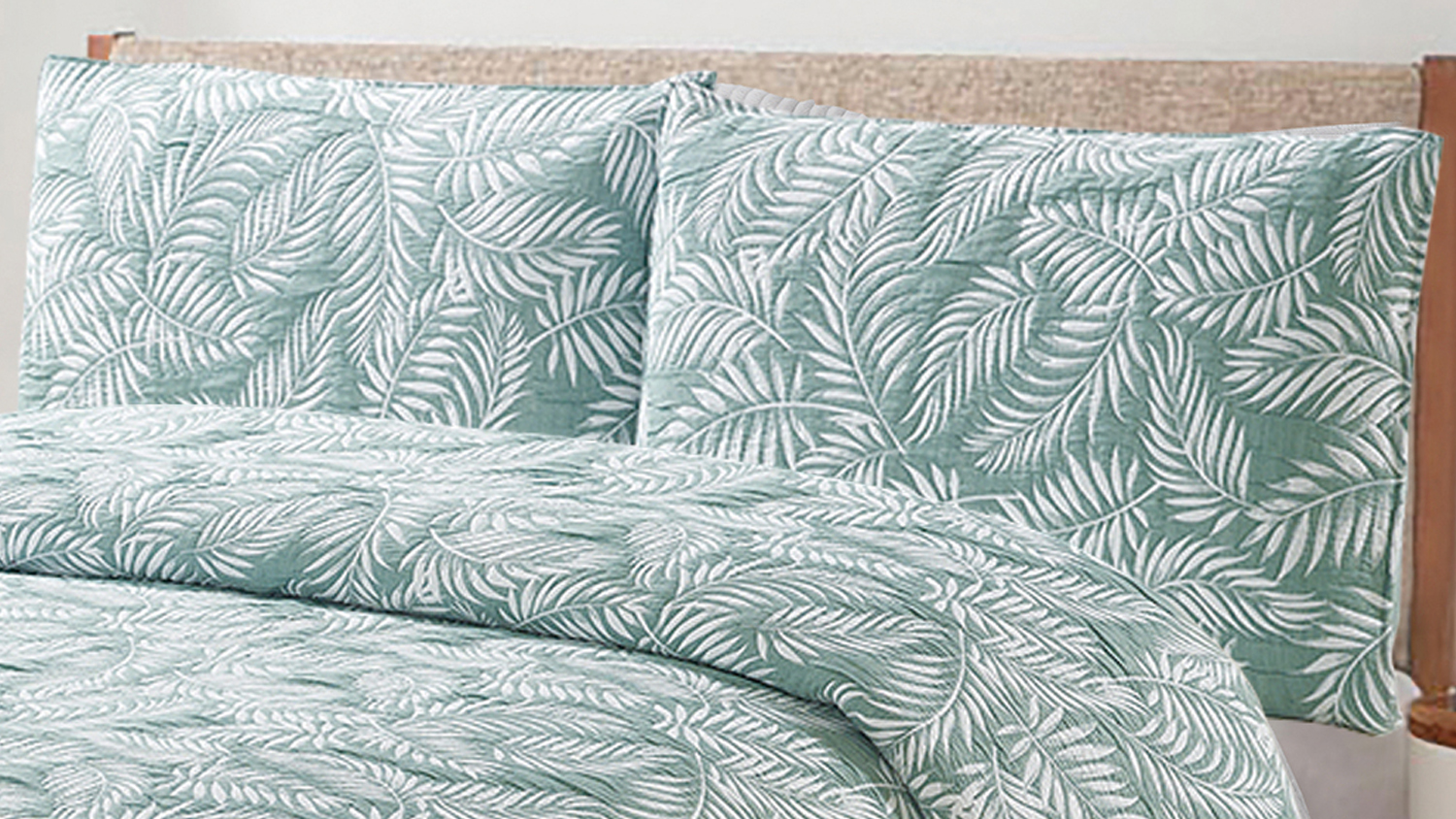 Close‑up of the bed pillows and coverlet, highlighting the quilted texture and fern leaf design in sage green and white