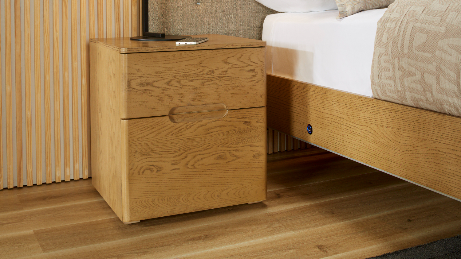 Resonance 2 Drawer Bedside Table in light wood finish positioned beside the bed