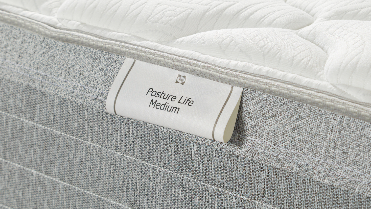 Detailed close‑up of the side label reading “Posture Life Medium,” showing the mattress fabric texture