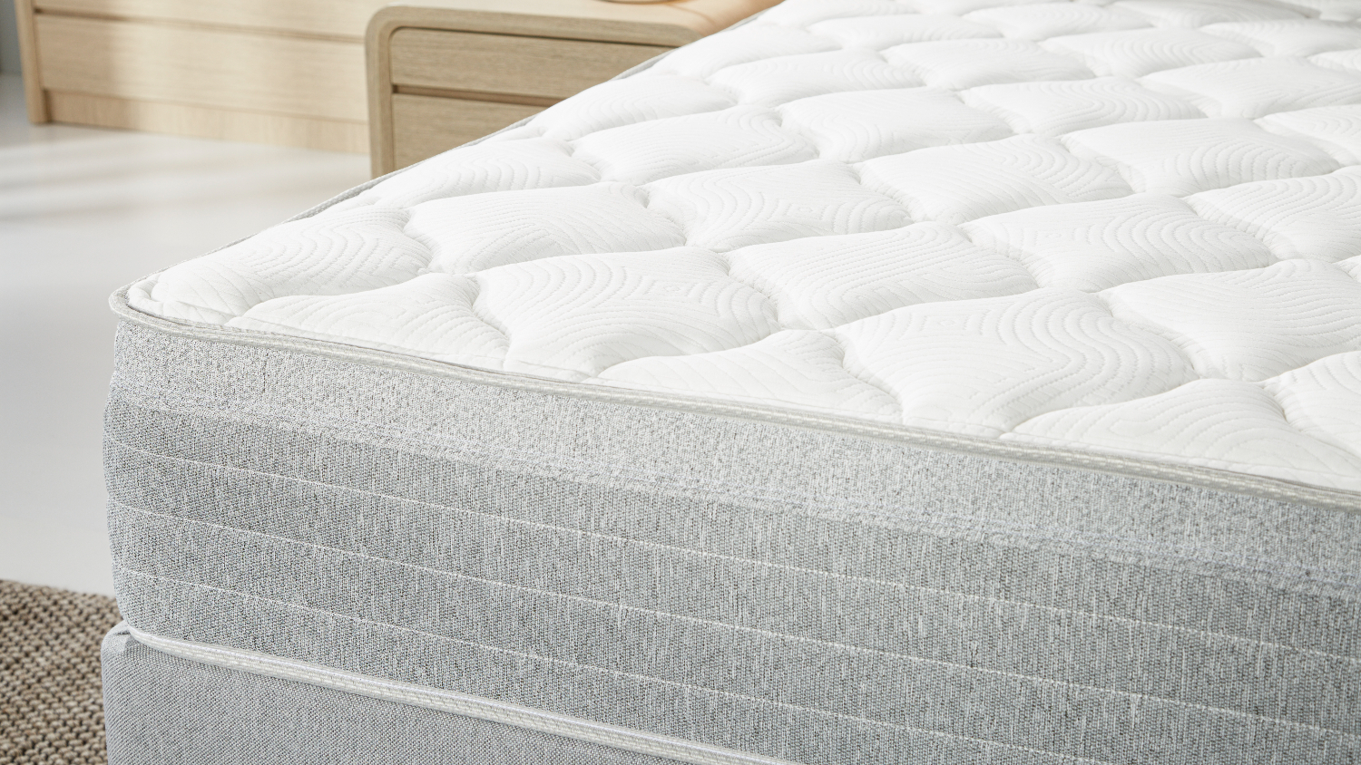 Side close‑up of the mattress edge, focusing on the soft quilted top layer and textured fabric