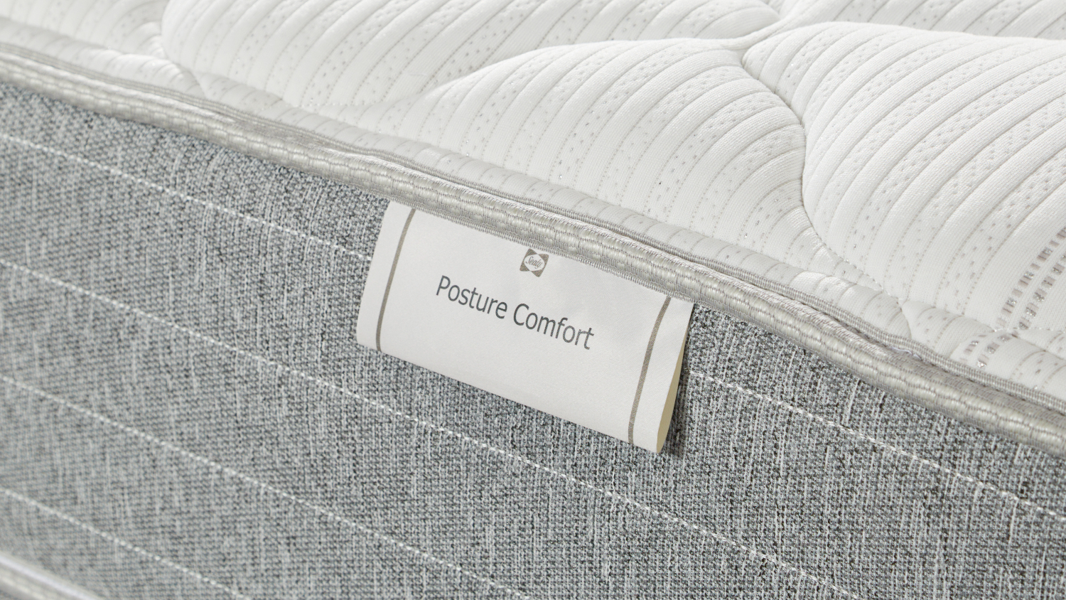 Branding tag on a Posture Life Comfort mattress showing the product name and gray fabric