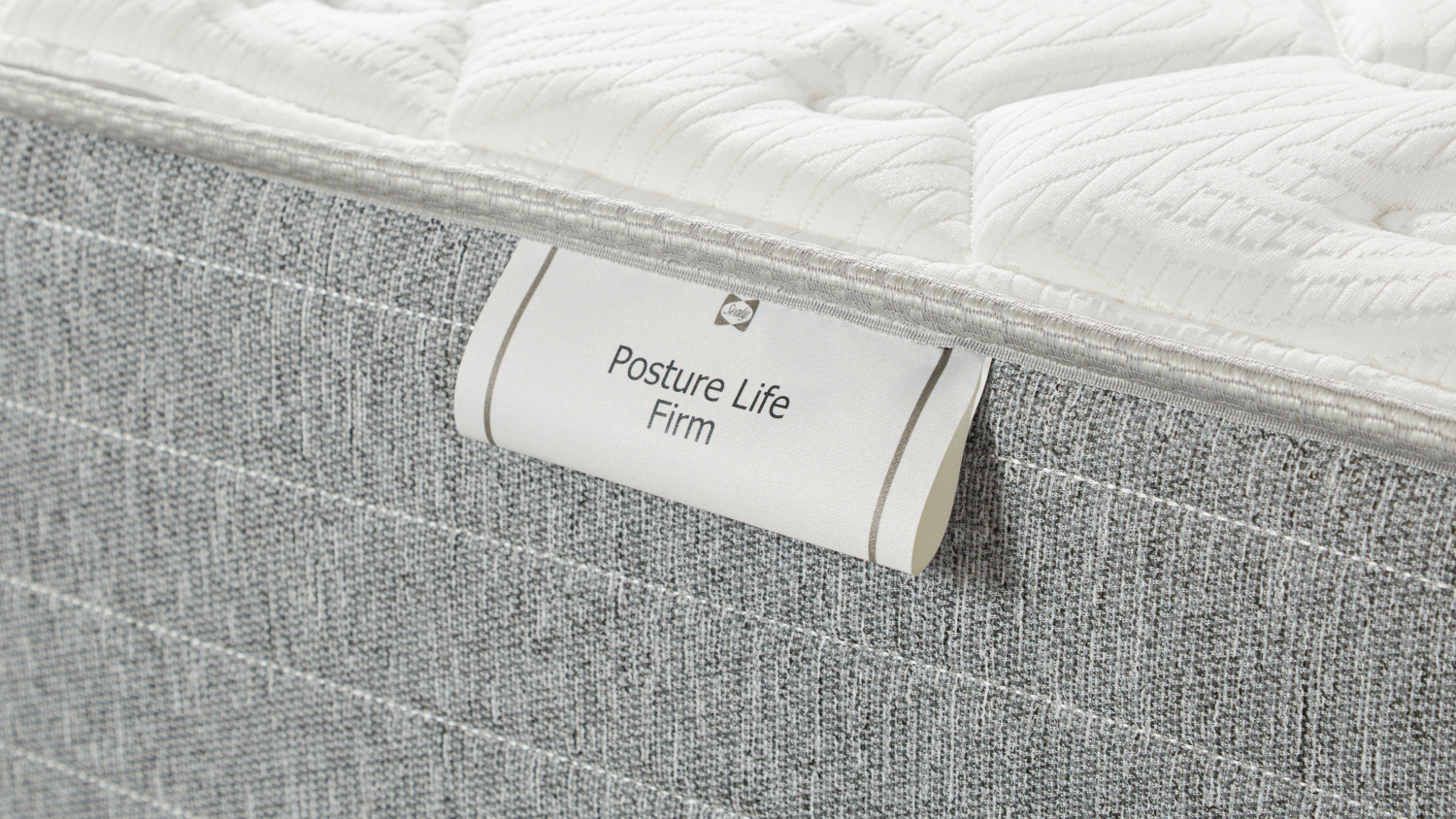 Detailed close‑up of the side label reading “Posture Life Firm” showing the mattress fabric texture