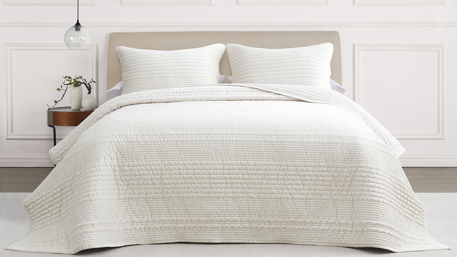 Front view of a queen bed styled with a ruched velvet coverlet in a soft natural cream tone