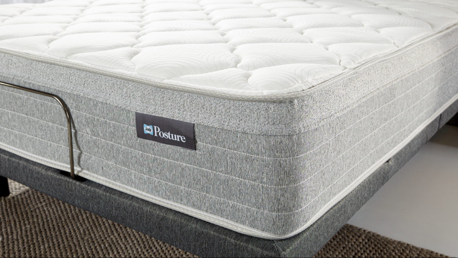 Close‑up of the mattress corner showing the white quilted comfort layer and textured grey side panel