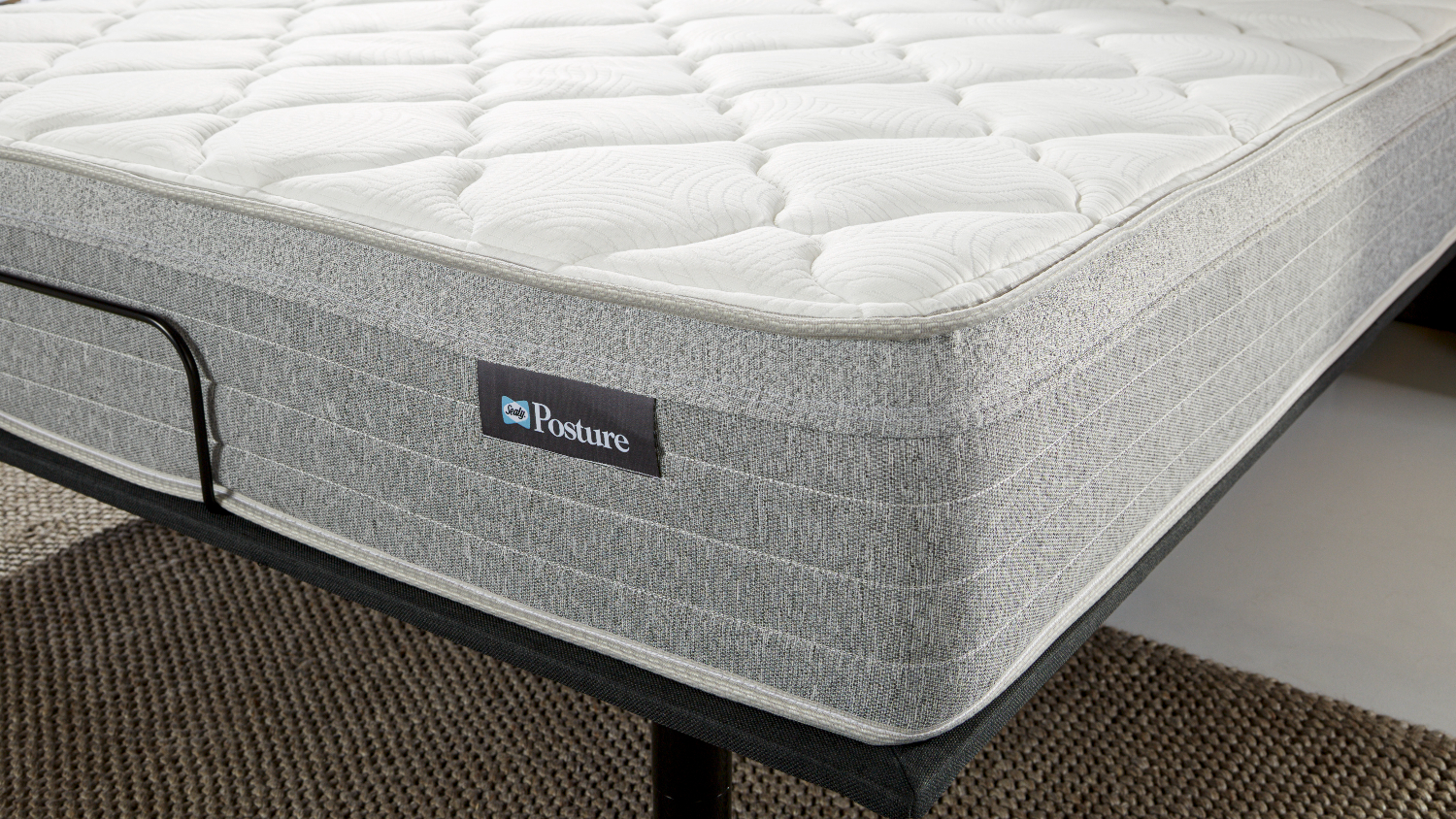 Close‑up of the mattress corner highlighting the white quilted comfort layer and textured grey side panel