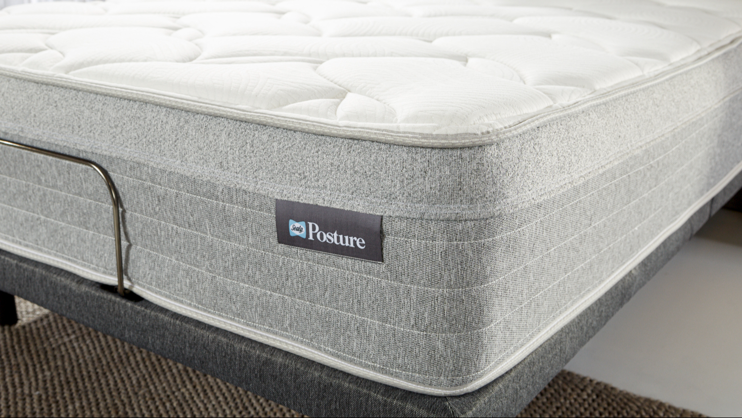 Close‑up of the mattress corner showing the grey textured side panel and stitched Sealy Posture label