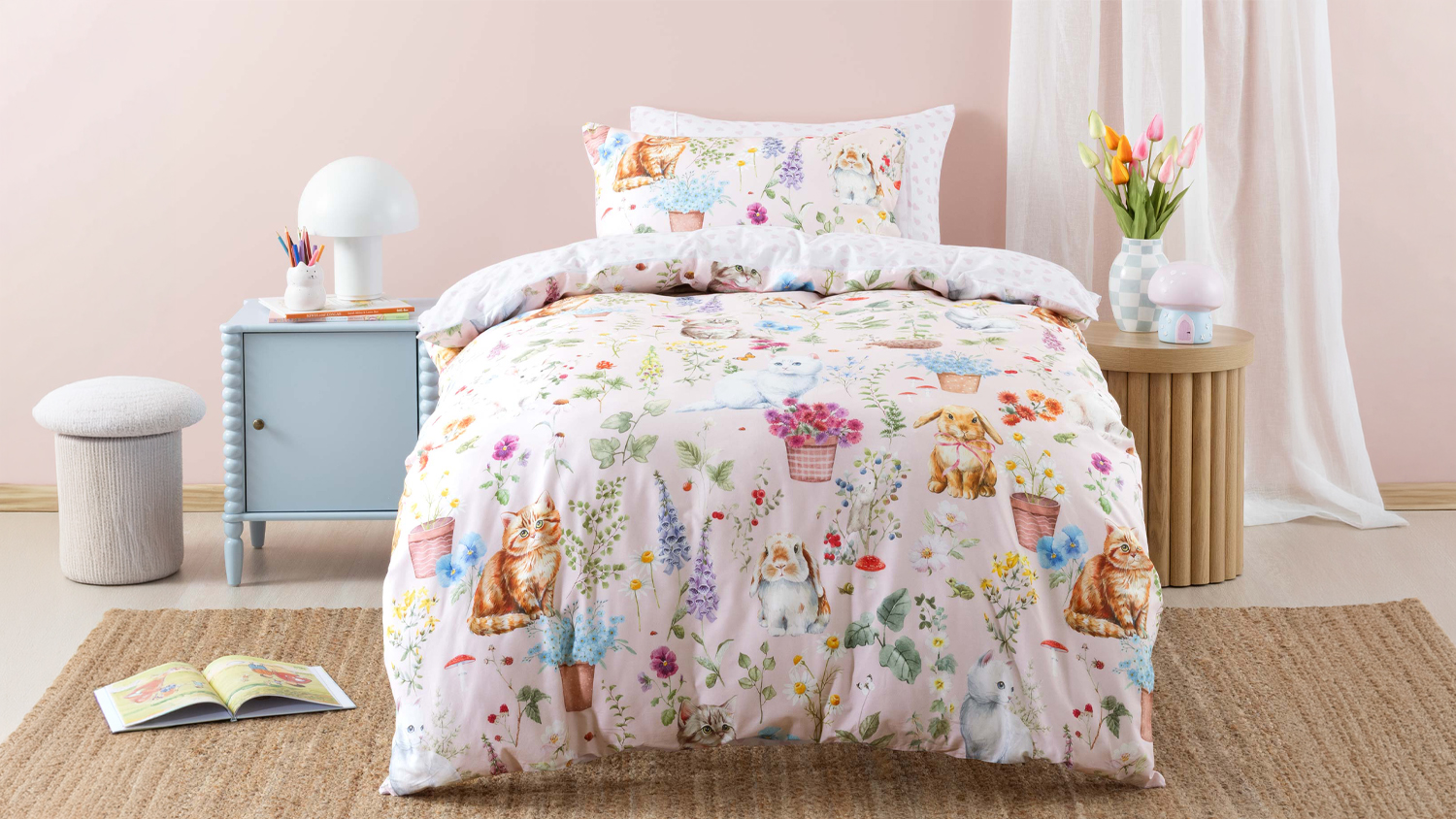 A child's bed featuring the Woodland Whiskers duvet set with a pink watercolour print of kittens and garden flowers