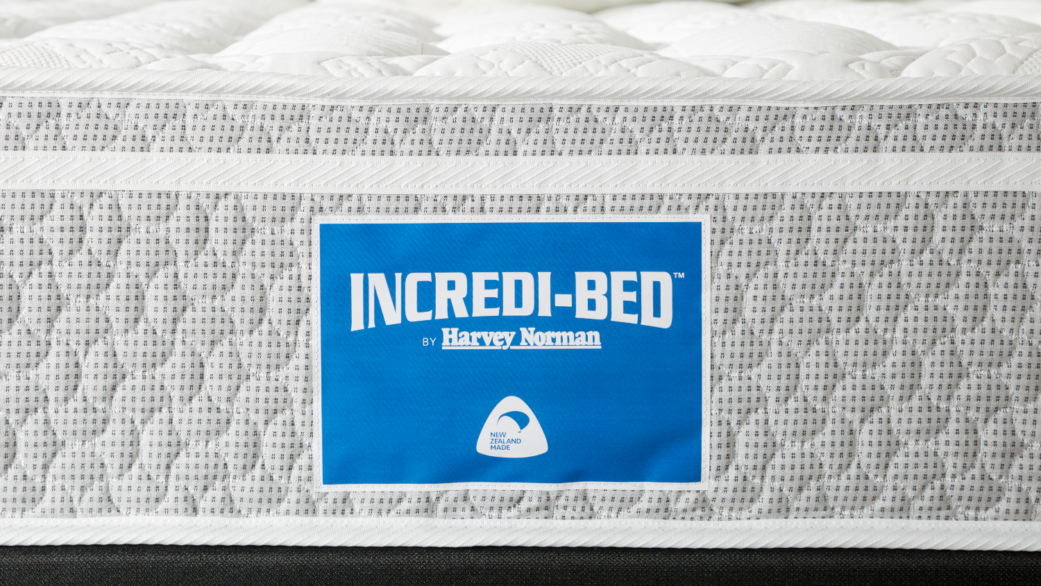 Detailed side view of the Incredi‑Bed mattress with visible logo label, stitched fabric, and layered construction design