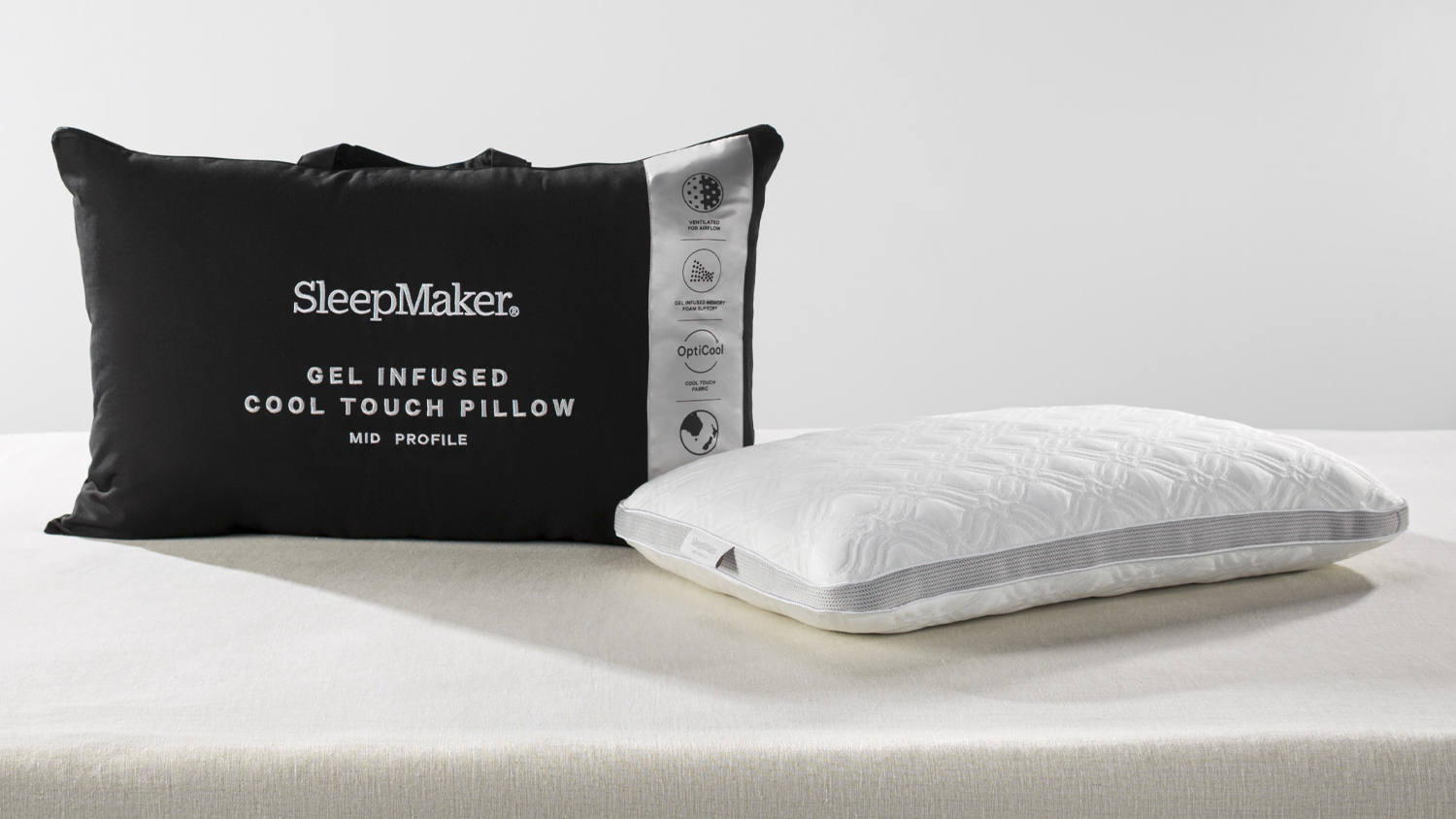 SleepMaker gel-infused cool touch mid profile pillow in white textured fabric next to its black zippered carrying bag