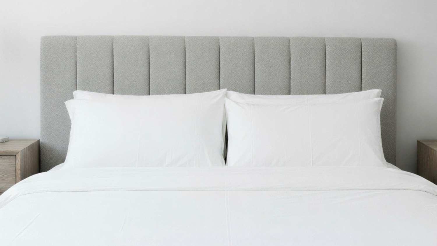 Nile Super King upholstered headboard fabric with vertical panels, paired with white pillows in a bedroom setting