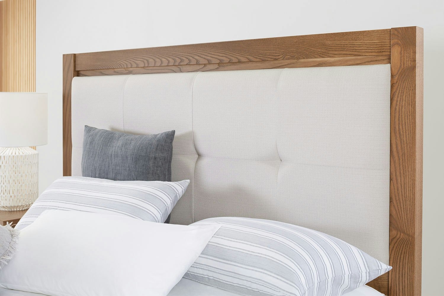 Milford Standard Californian King Padded Headboard with striped pillows, and bedside lamp in a neutral bedroom