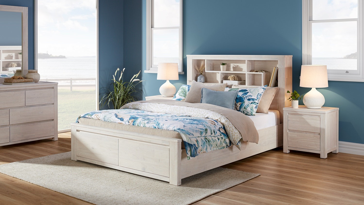 Palm Beach Storage King Bed Frame with white bed, blue walls, matching nightstands, lamps, dresser, and large windows
