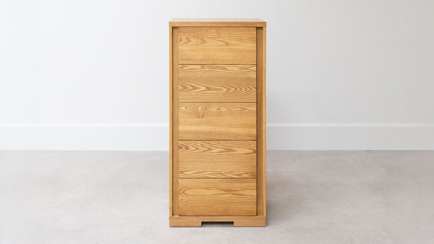 A modern, light oak 6-drawer tallboy with a natural wood grain finish, standing vertically against a plain white wall