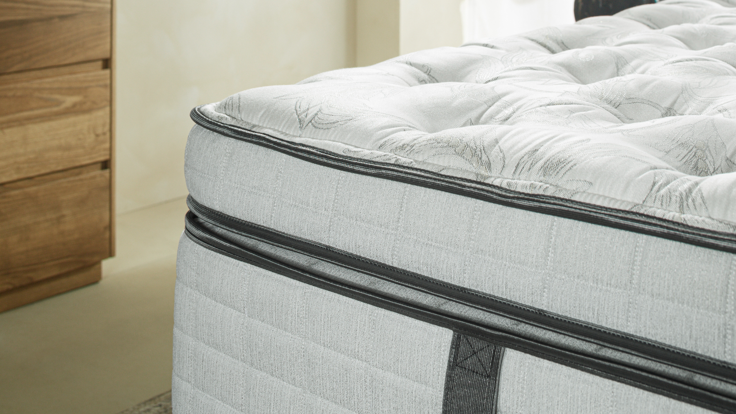 Angled close-up of the corner of a Graphite Soft mattress showing the textured fabric edges