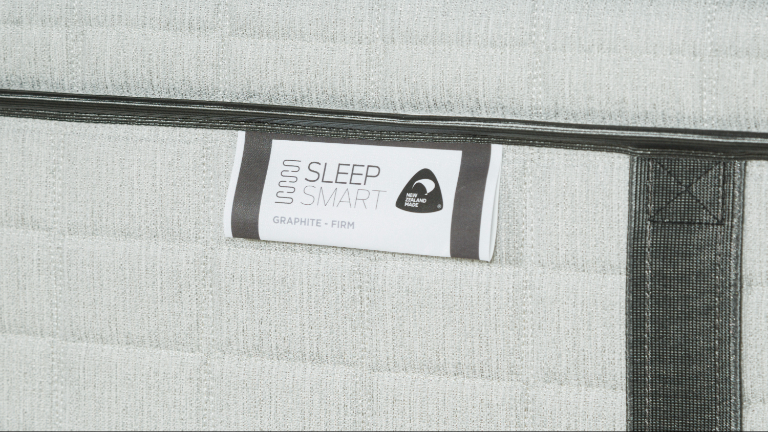 A close-up view of the sleep smart mattress’ graphite-firm tag