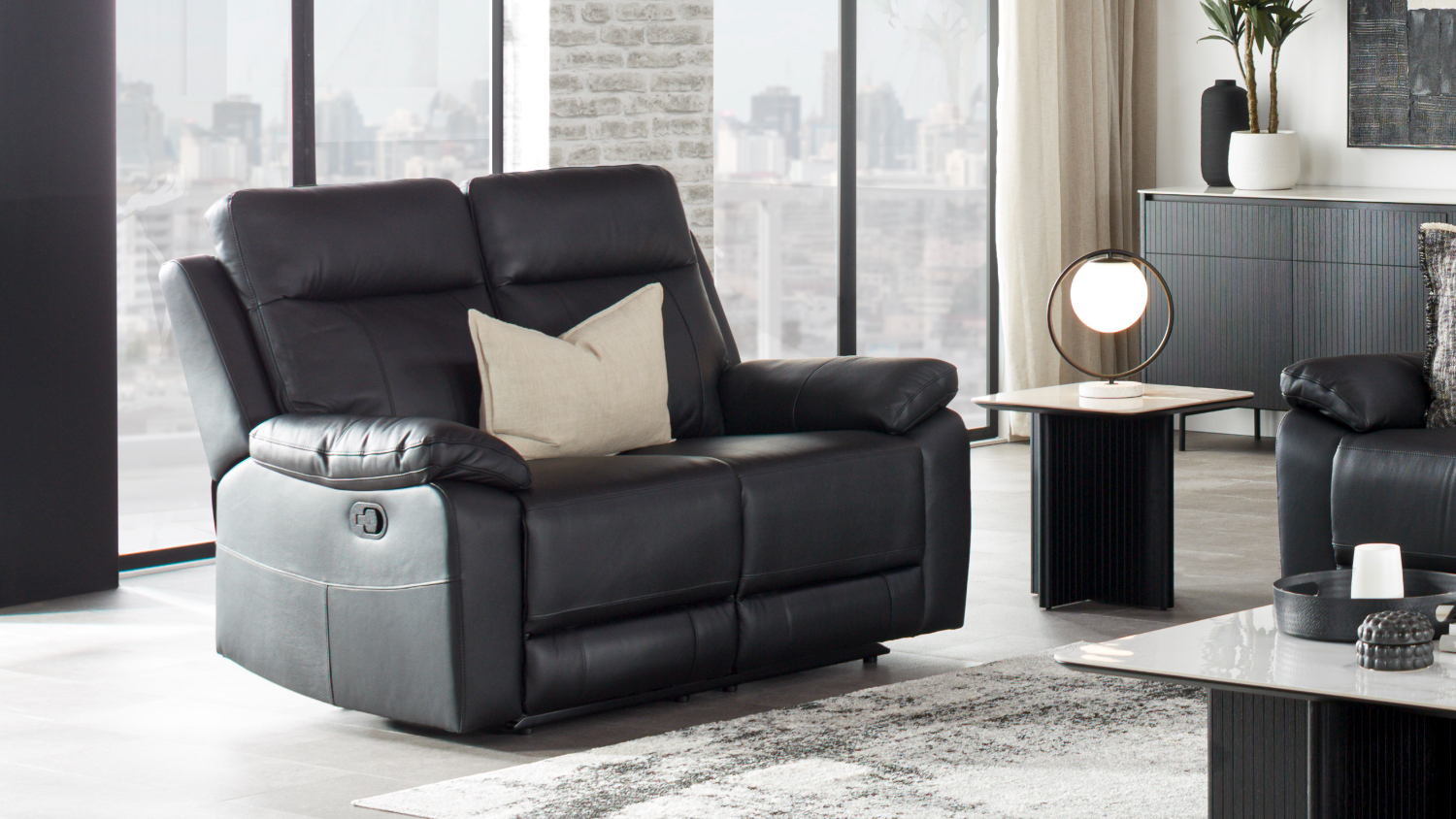 Front-facing view of a contemporary Nomad 2 Seater Leather Recliner Sofa in a bright, modern living room