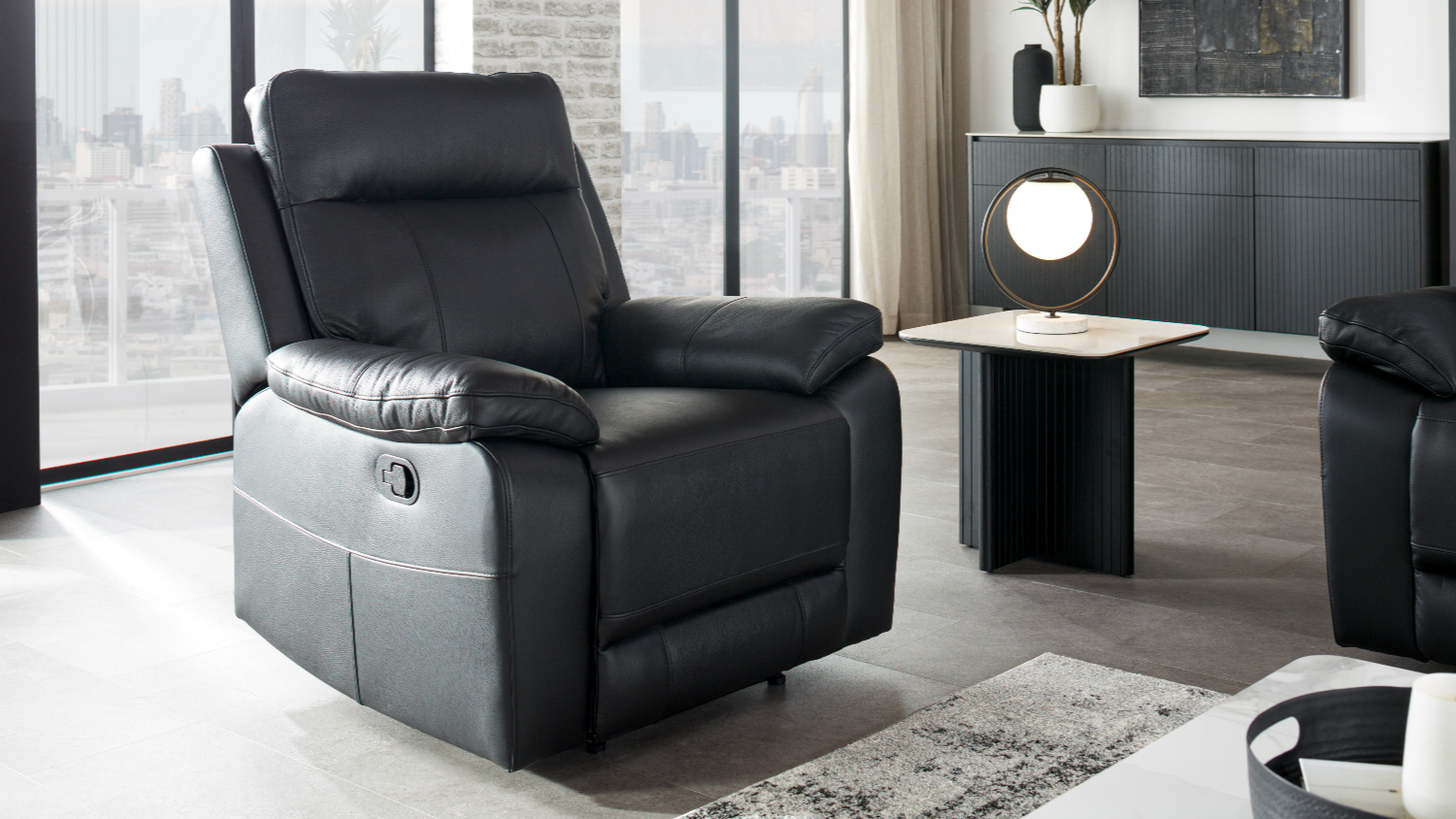 Nomad Leather Recliner Chair in platinum colour, featuring a high backrest and plush padded armrests in a modern room