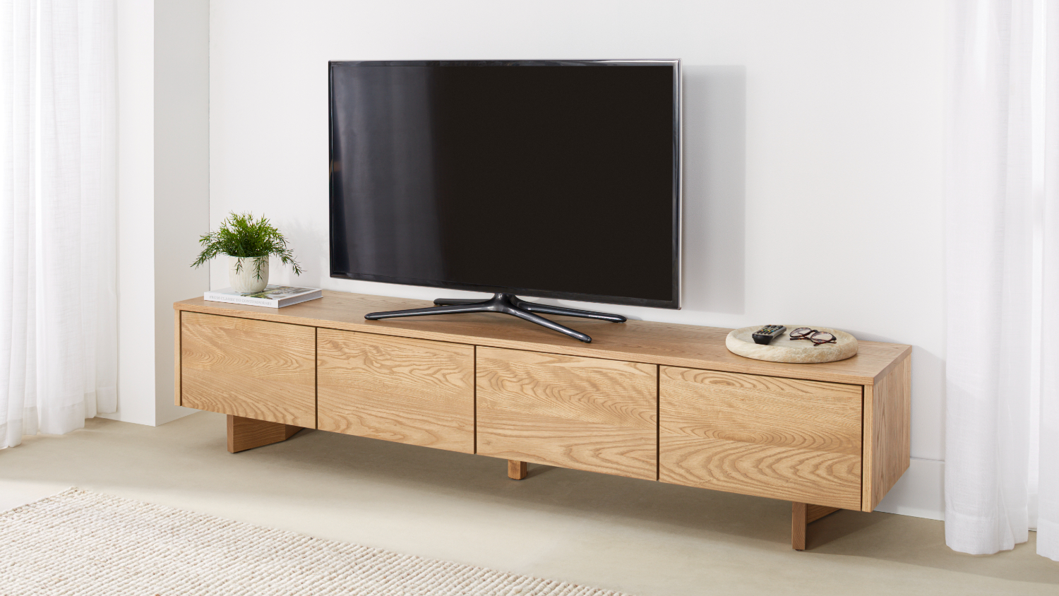 A minimalist Sinclair 2000mm Entertainment Unit with a TV on top placed in a bright living room