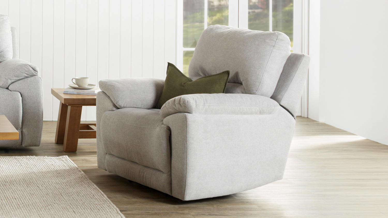 Modern Featherstone fabric recliner armchair styled with a decorative cushion in a sunlit room