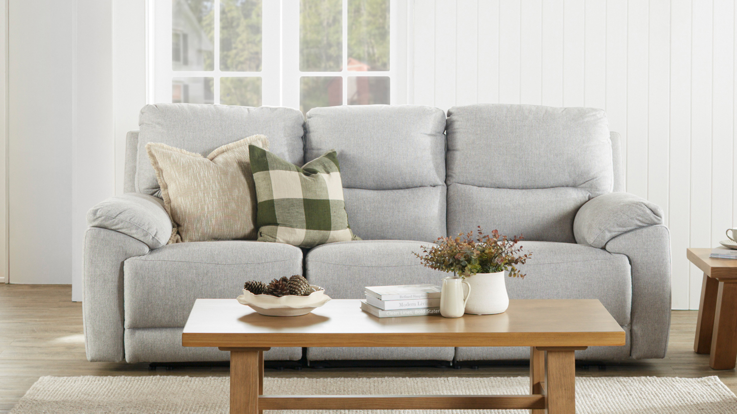 A modern Featherstone 3-Seater Fabric Recliner Sofa with decorative cushions in a bright living room