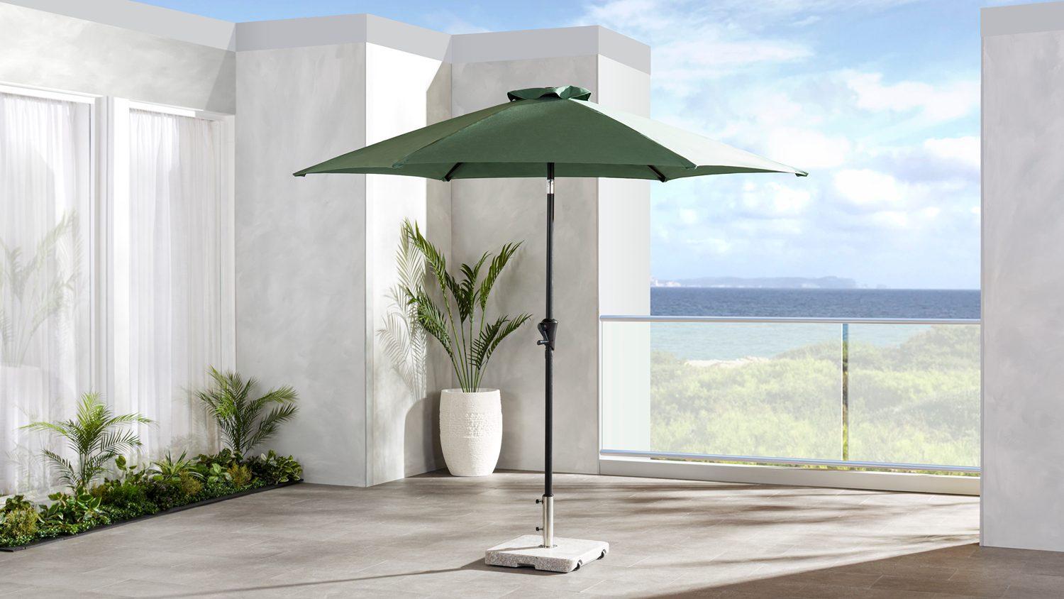 Pakiri 2.7m outdoor umbrella with a dark green polyester canopy and black steel centre pole, displayed open on a patio