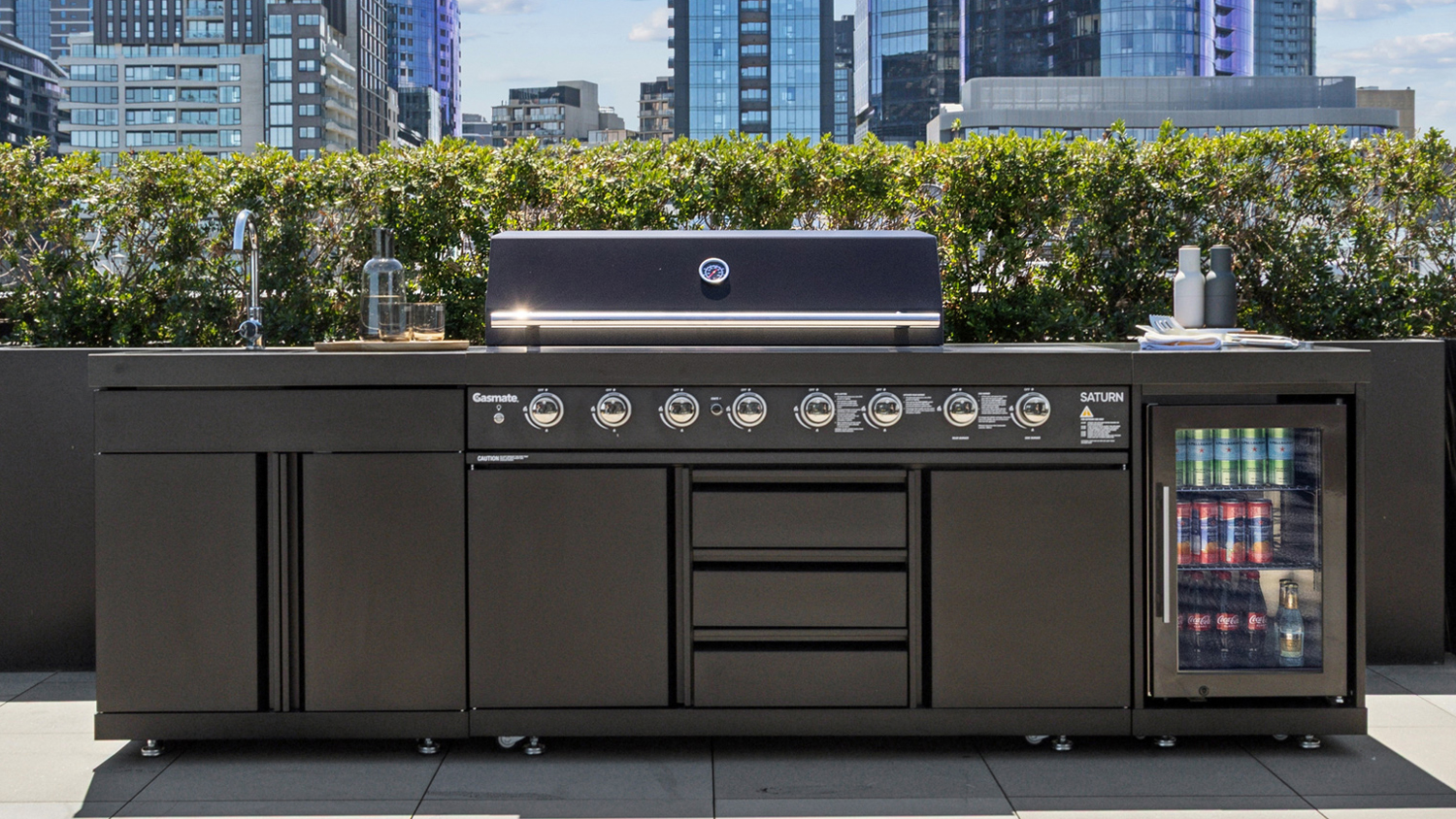A black Gasmate Saturn 6-Burner Gas BBQ Outdoor Kitchen with Sink, Storage and Fridge