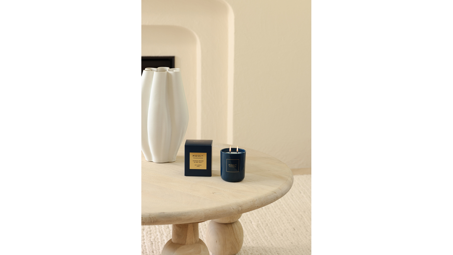 Minimalist room featuring a lit blue candle and box near a white vase