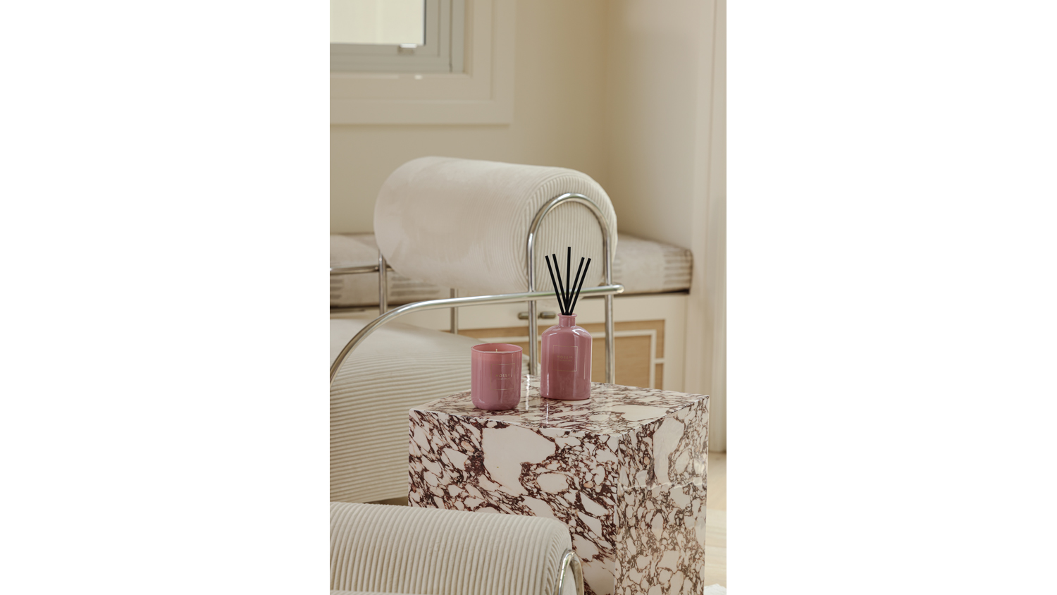 Modern room highlighting a candle and reed diffuser on a marble table