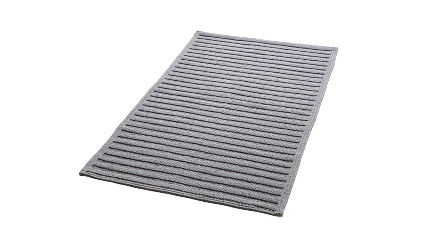 A ribbed grey Baksana Nova Luxury Bath Mat is placed beside a modern freestanding bathtub