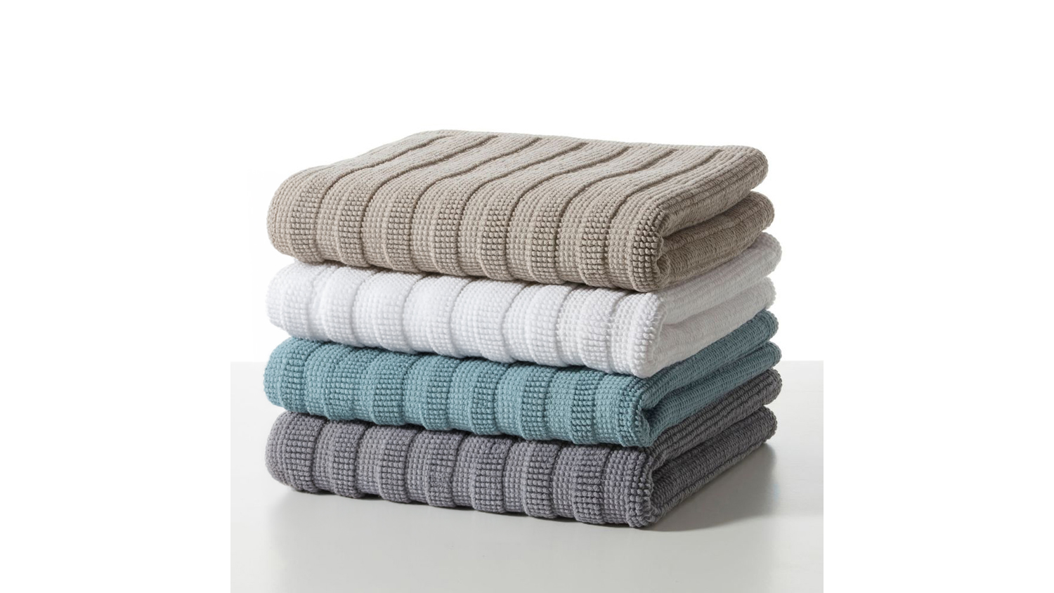 Four stacked ribbed Baksana Nova Luxury Bath Mats in Fog, Optic White, Baltic Green, and Magnetic Grey colour options