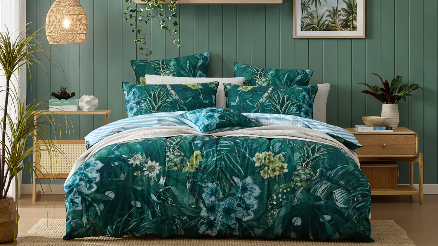 Dark teal tropical floral and pineapple print duvet cover set with striped reverse, styled bed front view