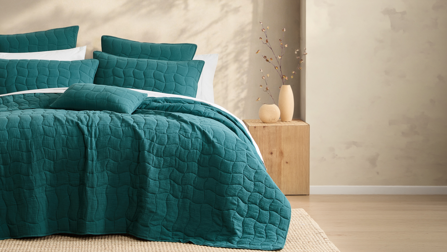 Teal Halcyon Lagoon coverlet set styled on a bed in a sunlit neutral bedroom