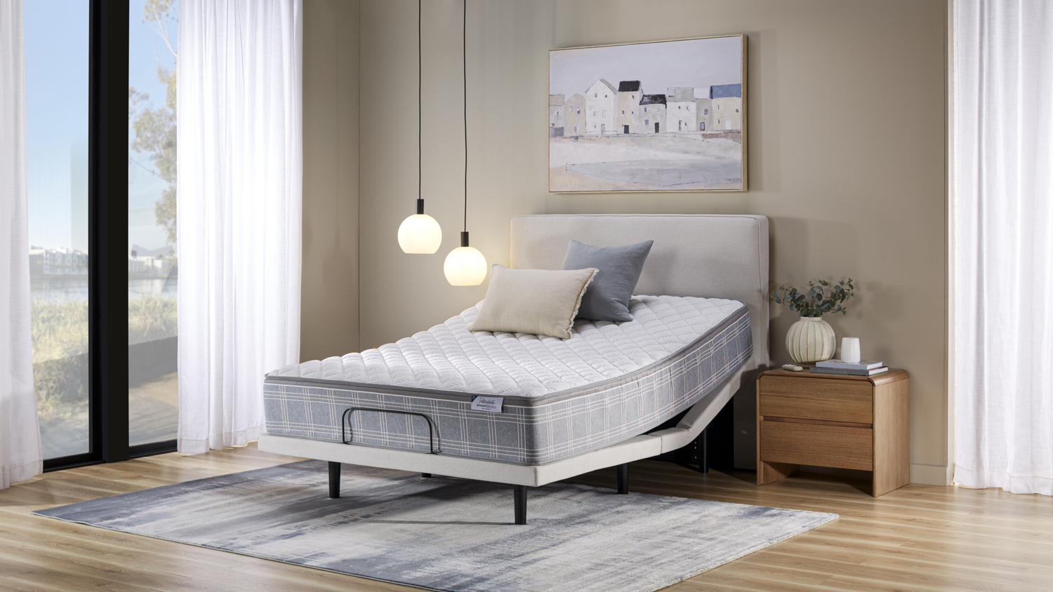 Grey adjustable bed base with quilted mattress raised at the head
