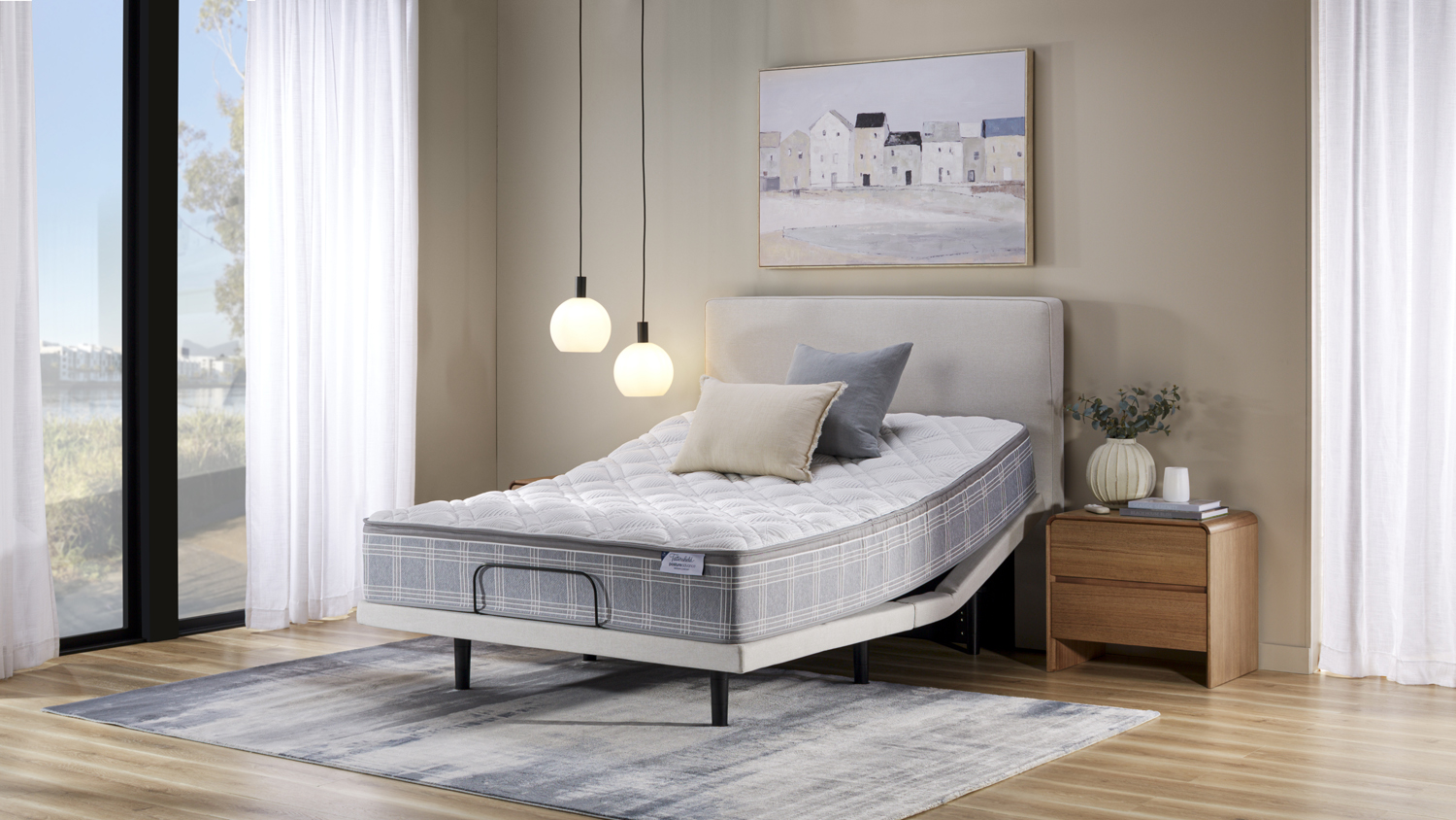 Grey adjustable bed base with quilted mattress raised at the head