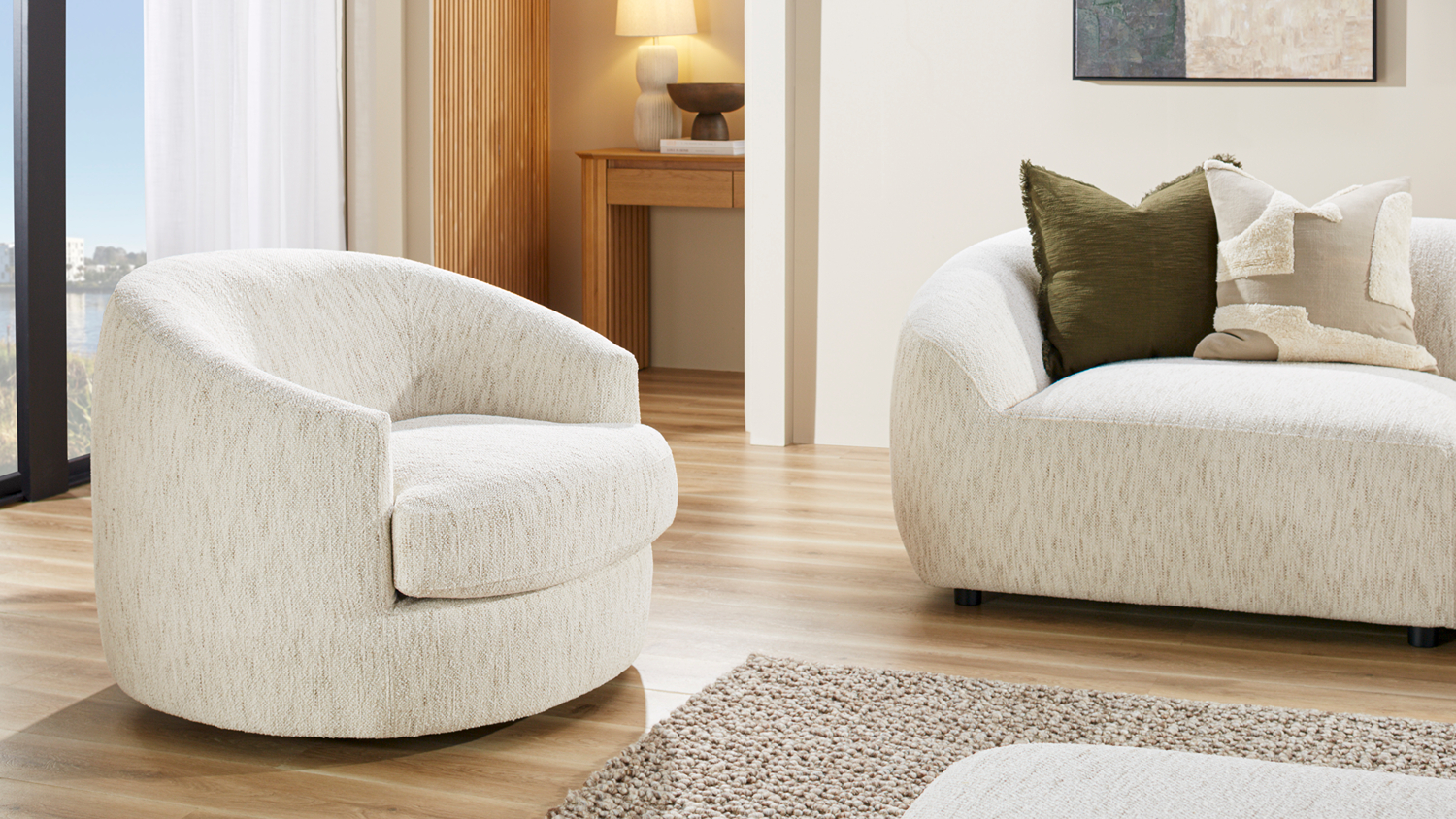 Villa Fabric Swivel Chair in Optical positioned beside a matching cream couch on light wood floors
